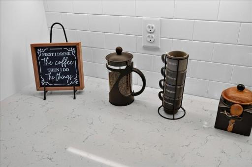 PHOTO OF A DIFFERENT HOME WITH SIMILAR PLAN AND FINISHES. Kitchen highlights include a Ceramic Tile Backsplash, Quartz Countertops, and Under Cabinet Lighting.