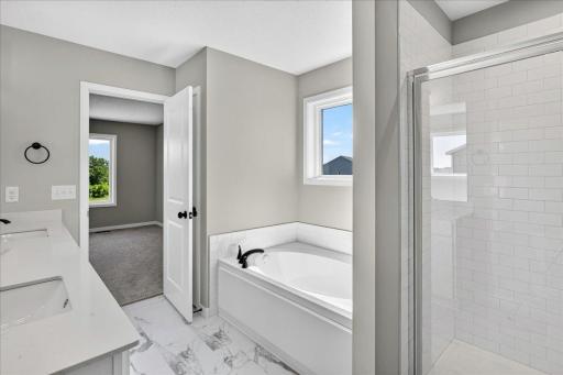 PHOTO OF A DIFFERENT HOME WITH SIMILAR PLAN AND FINISHES. Primary Suite Deluxe Bath features a Soaking Tub, Separate Shower with Tile Wall Surround, LVT flooring, and Linen Closet for added storage.