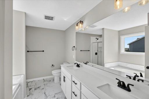 PHOTO OF A DIFFERENT HOME WITH SIMILAR PLAN AND FINISHES. Primary Deluxe Bath.