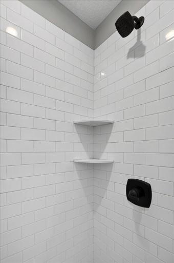 PHOTO OF A DIFFERENT HOME WITH SIMILAR PLAN AND FINISHES. Primary Deluxe Bath Shower features Tile Wall Surround with Shelves and a Shower Door.
