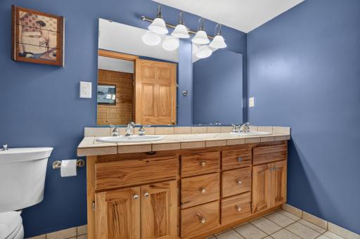 Main floor full bathroom features tile flooring and double sink vanity.