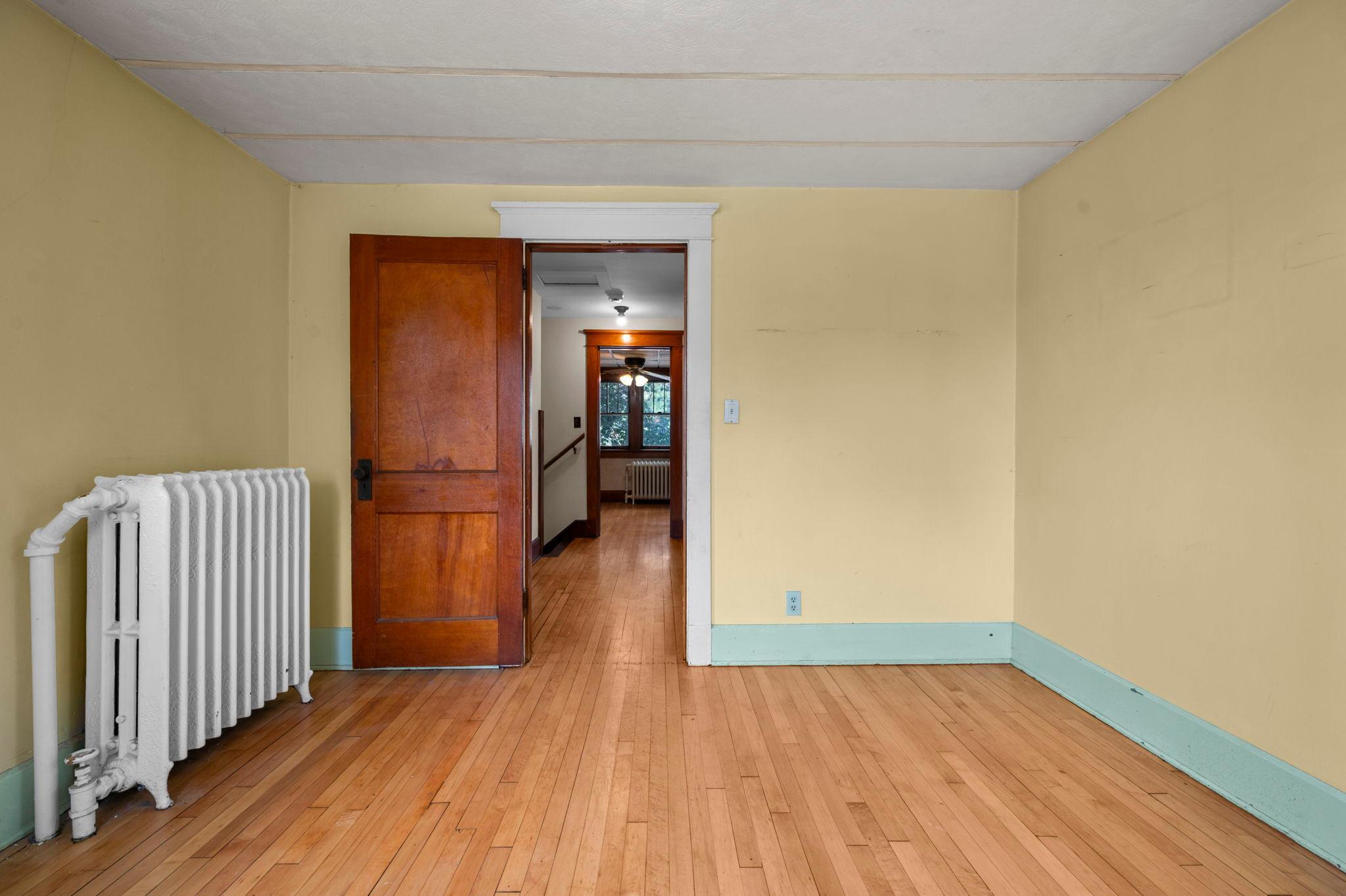 Sunny bedroom with original woodwork opens to the home's classic center hall.