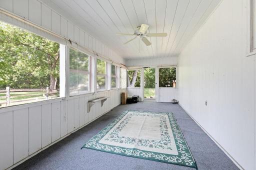 Side porch with charming paneled walls, ceiling fan, and views to your spacious yard