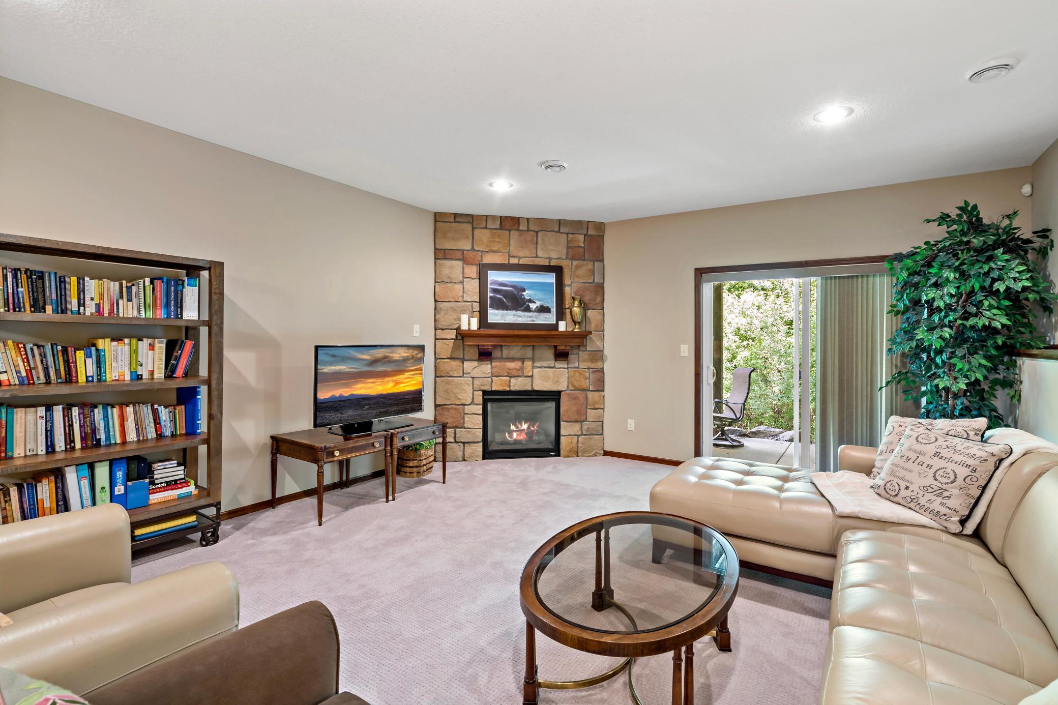 The gas fireplace with an impressive stone surround is a beautiful focal point for the lower level family room.