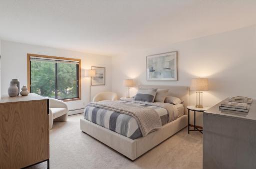 Spacious primary bedroom with plenty of room for a king-size bed and sitting area. Virtually staged.