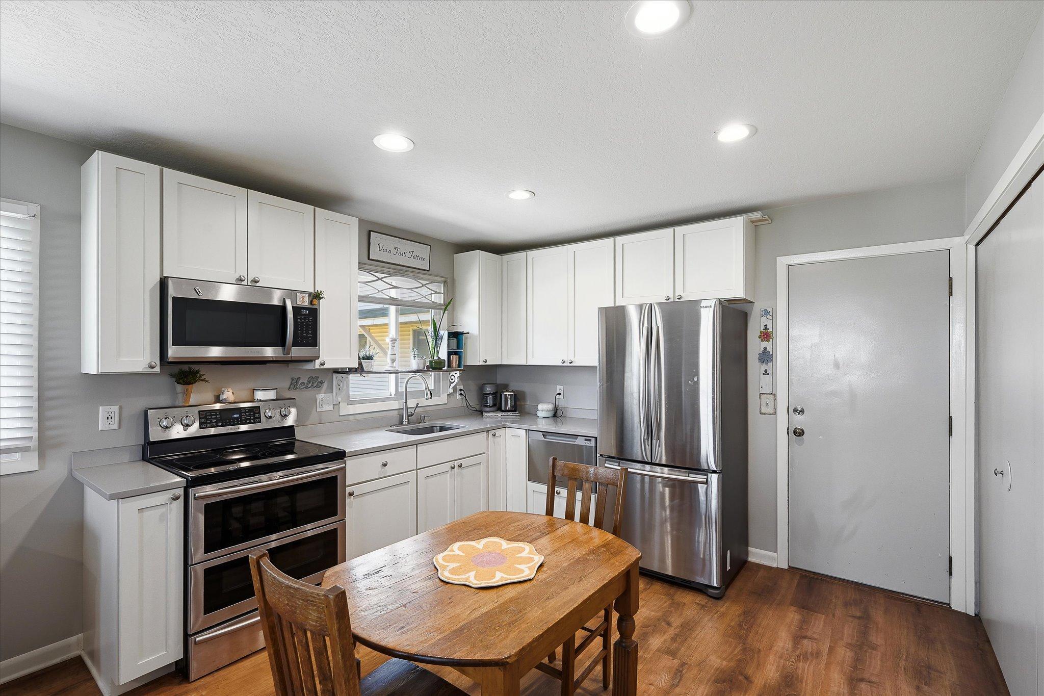 The kitchen was remodeled to open the floor plan, including white cabinets, quartz countertop, and stainless appliances.