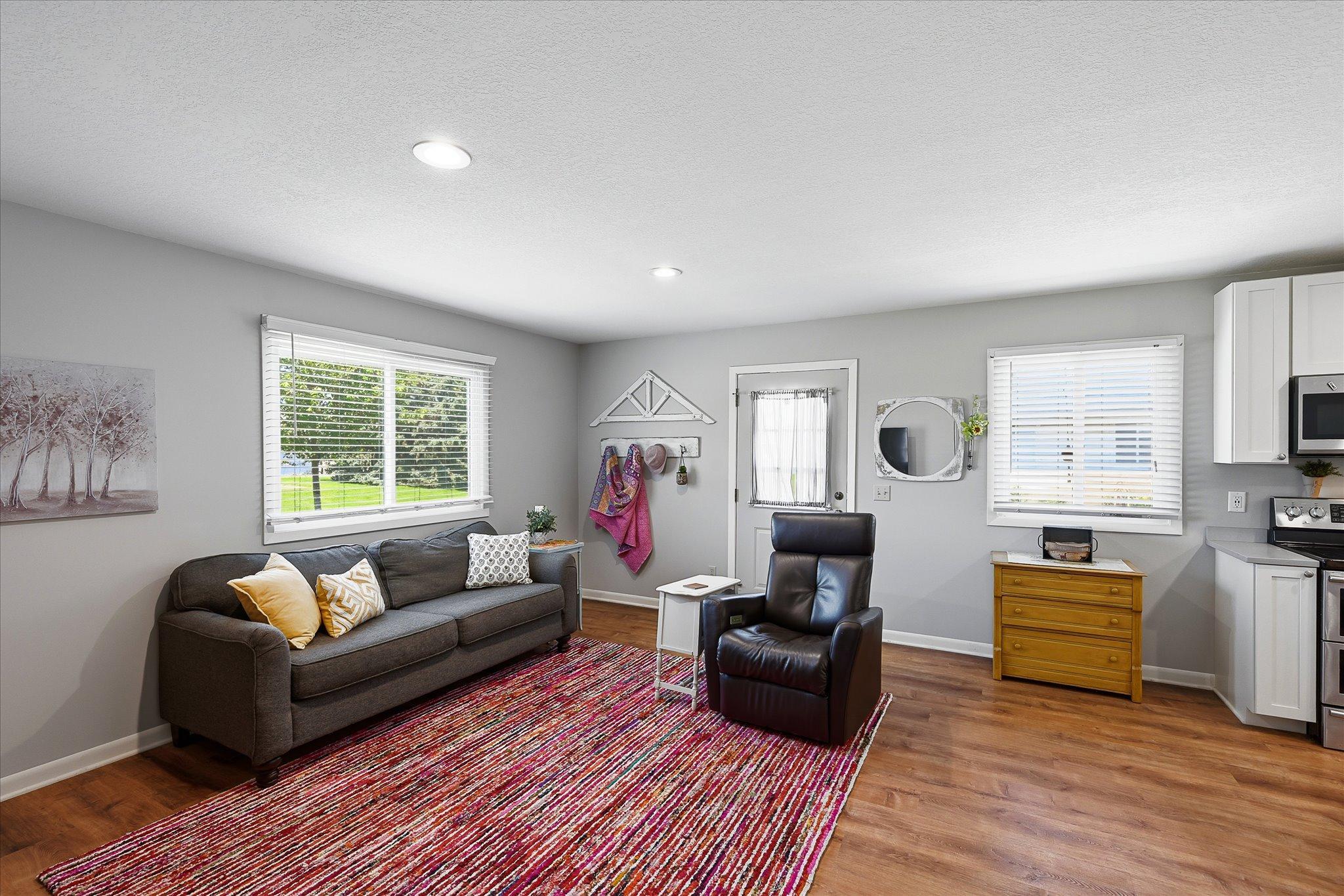 The luxury vinyl plank floors make this living space comfortable and transitional. A dining table could easily be used in the extra space shown here, leaving space for an island or work table in the kitchen.