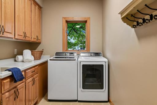 Laundry area with a sink and plenty of storage. There is a laundry shoot that empties into the upper cabinet above the sink that is from the upper level