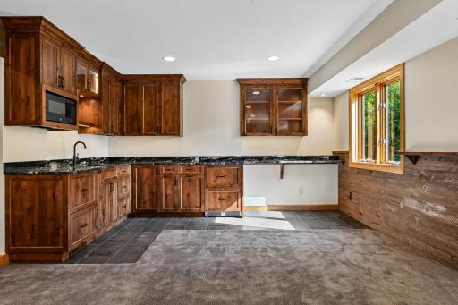 Nice sized wet bar that features custom cabinetry, fridge, dishwasher, bar seating and accent lighting