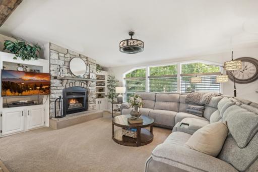 Featuring a wall of windows with a view of the double lot yard, and a chic stone-front fireplace complete with built-in display shelving.