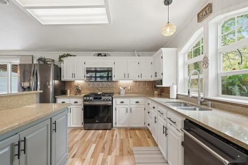 The tin backsplash and neutral wood flooring reflect the light coming through the windows and brighten the space.