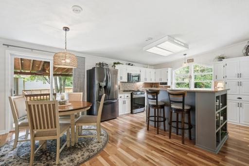 The eat-in vaulted kitchen offers an elevated center island with seating, stainless steel appliances, view of the sprawling backyard, and sliding door access to the deck.