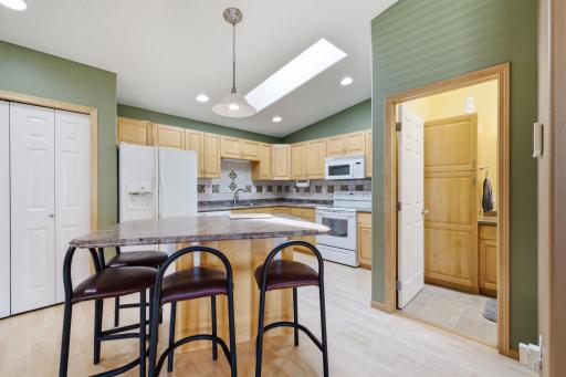 Kitchen features a breakfast/bar island with storage, backsplash, skylight, recessed lighting