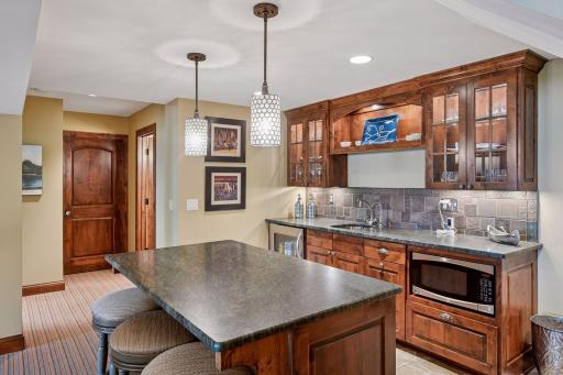Wet bar on the lower level with microwave, beverage fridge, and room to sit at the island