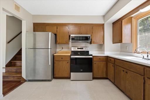The generously sized kitchen blends classic character with thoughtful updates, featuring abundant cabinetry, newer stainless steel appliances, and plenty of countertop space for meal preparation.