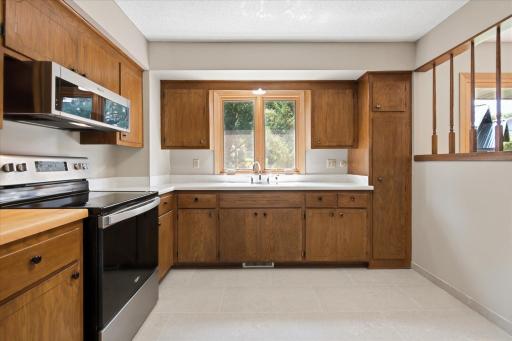 A large window above the sink brings in peaceful backyard views while generous cabinet storage and functional workspace make this kitchen as practical as it is inviting.