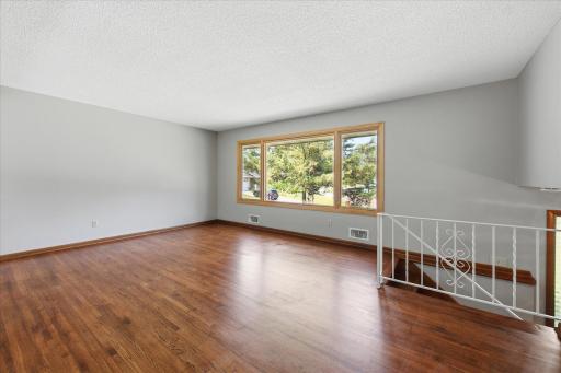 Natural light pours through the oversized picture window, highlighting beautifully refinished hardwood floors and creating an inviting setting for everyday living and entertaining alike.
