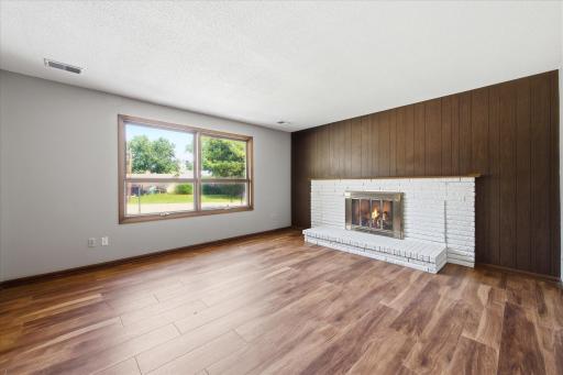 Just off the foyer, the cozy family room offers a classic wood-burning fireplace, large picture window, and durable flooring, creating the perfect gathering space for relaxing evenings.