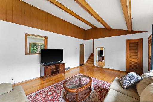The living room has a pass-through window to the kitchen on the left, doorway to the kitchen on the left, stairs leading to the upper/fourth floor located near the doorway and a coat closet to the far right near the front door.