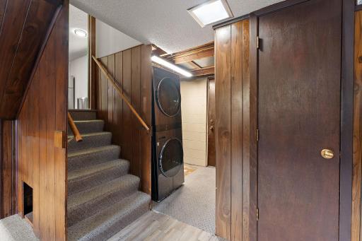 The second floor has the laundry room with access to the backyard patio through the door beyond the stacked washer and dryer. The stairs lead up to the third floor with the kitchen. The 1/2 bathroom is located behind the closed door on the right.