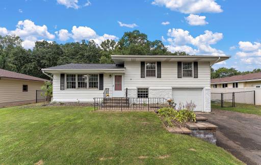The front of the home has a paved driveway, a one car tuck-under garage and a well maintained yard to the curb.