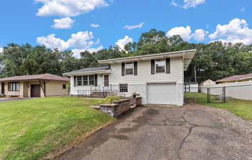 The tuck-under garage is convenient and the driveway offers additional space for parking. A small yard shed is just visible to the right in the backyard.