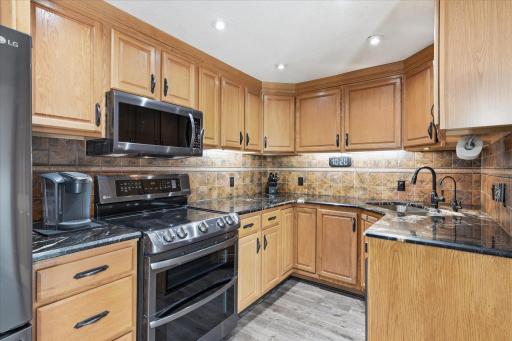 Beautifully appointed kitchen showcases granite countertops, a decorative tile backsplash, under-cabinet lighting, newer stainless steel appliances, and an abundance of cabinetry providing exceptional storage and workspace.