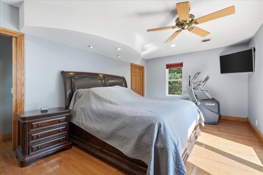 Spacious primary suite showcases beautiful hardwood floors, updated windows, recessed accent lighting, and an elegant tray ceiling detail that adds architectural character.