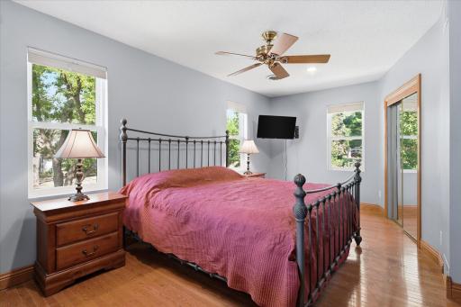 Spacious secondary bedroom showcases rich hardwood floors, updated windows that flood the room with natural light, recessed lighting, and a generously sized closet, creating a bright and comfortable retreat.