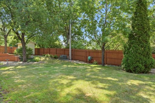Private, fully fenced backyard offers a beautiful blend of mature trees, lush green space, and professional landscaping, creating a peaceful setting for outdoor activities, pets, or simply relaxing.