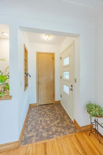 Step into the welcoming entryway featuring original tile, a cute coat closet, and a charming original built-in wall shelf that provides convenient storage while preserving the home's classic character.