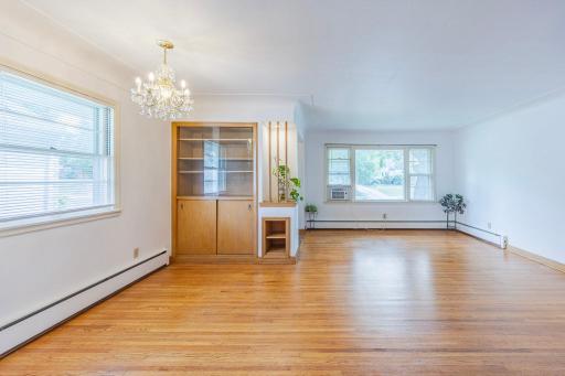 Another angle of the spacious living and dining area, showcasing the open layout, abundant natural light, and beautiful original hardwood floors.