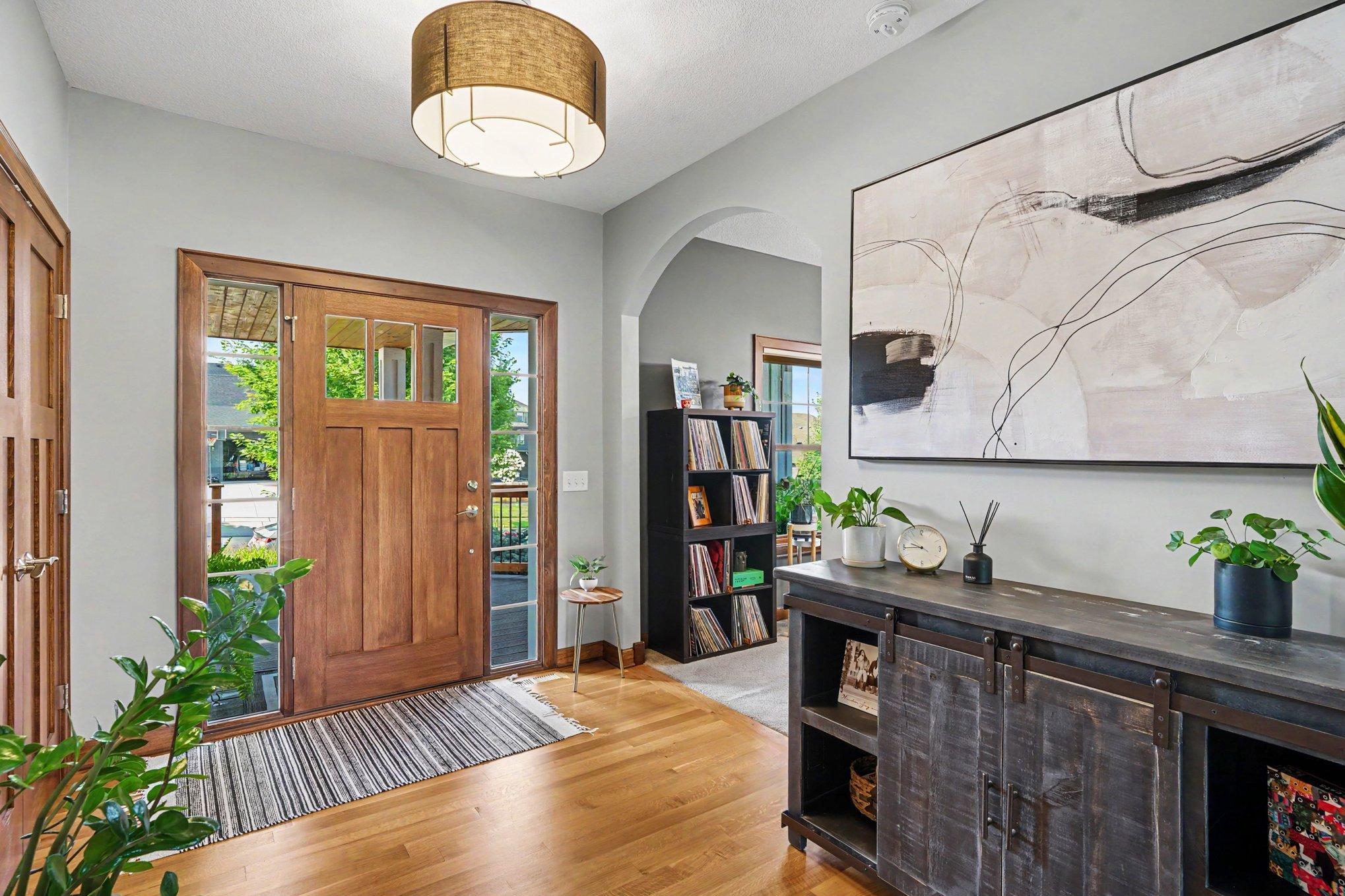 The spacious entryway into the home has a coat closet, new lighting, hardwood floors and a main floor office with a curved, open archway.