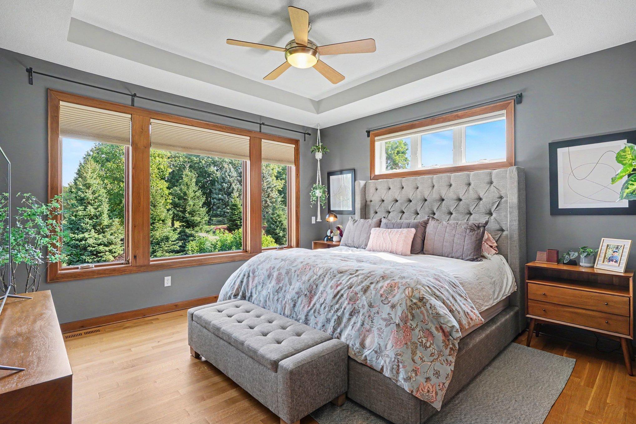 The primary bedroom is located behind the living room and offers so much light with the triple window and transom windows above the bed. Features include hardwood floors, a tray-vault ceiling and a ceiling fan.