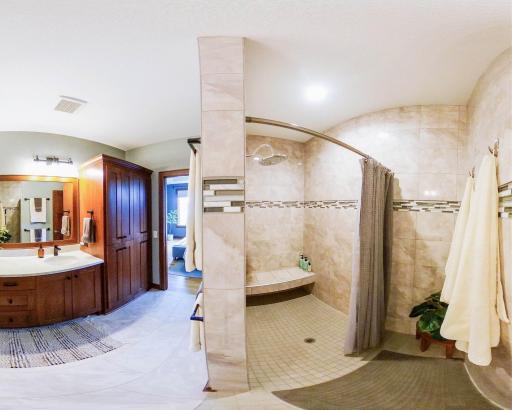 The walk-in tiled shower has a bench seat and is adjacent to the vanity. The toilet room is next to the shower.