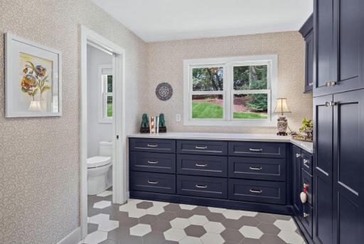 The mudroom/storage with the 2nd half bathroom right off of the garage with AI enhanced grass.