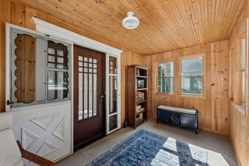 Light-filled enclosed front porch with warm woodwork and charming original character is also insulated.