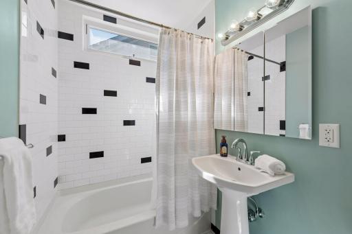 Updated main-level bath features crisp subway tile with playful contrasting accents and a classic pedestal sink.