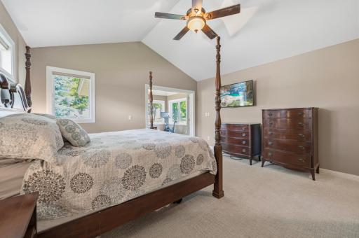 The spacious primary suite offers comfort, privacy, and direct access to the sunroom. Large windows fill this space with light.