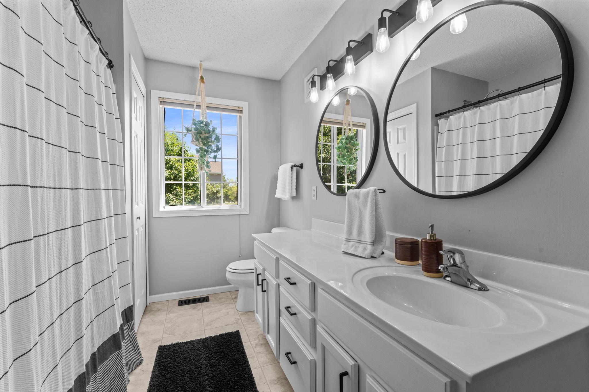 The walk-through full bathroom features an extended vanity with plenty of counter space, along with a linen closet for added storage.