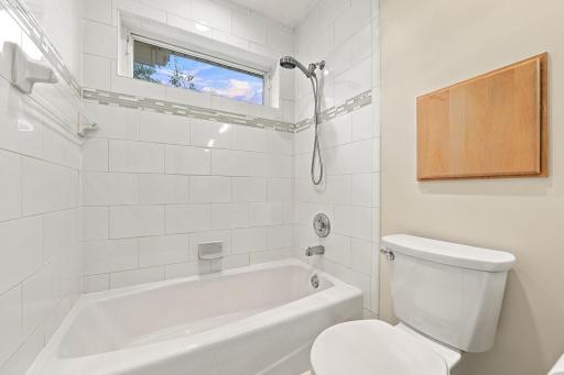 Natural light and warm cabinetry soften the clean finishes of the bath.