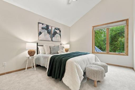 A large window fills the bedroom with natural light and views of the surrounding landscape.