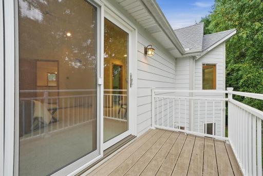 An upper-level deck overlooks the home’s lush, established grounds.