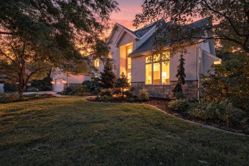 Warm interior light and mature trees set the scene at sunset.