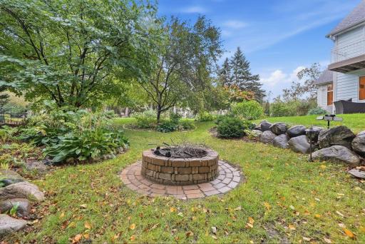 A circular firepit area creates a natural destination within the landscaped yard.