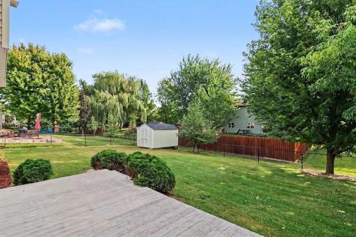 Fully fenced backyard with maintenance deck, mature trees, and garden shed.