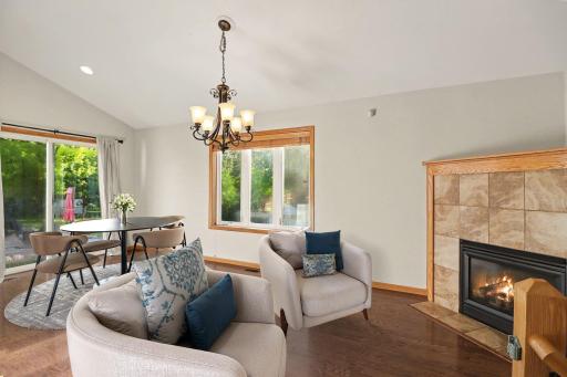 Main-level living room with vaulted ceiling, hardwood floors, and an open connection to the kitchen. virtually staged to show potential)