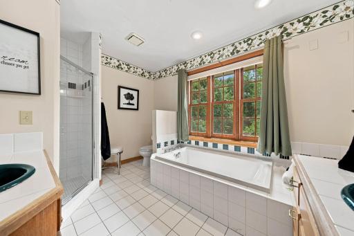 Primary bath has separate tub and shower with floor to ceiling tile.