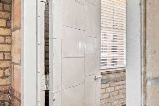 Original fire door beckons you into the primary bedroom...