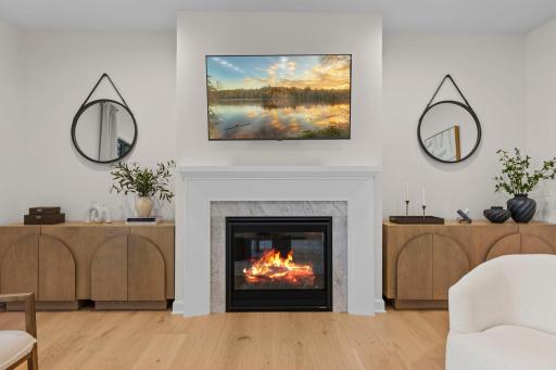 Stunning fireplace with marble surround serves as the focal point of this inviting living space, complete with custom built-ins and warm wood floors.